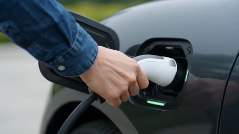 hand plugging a charger into the port of a modern electric car