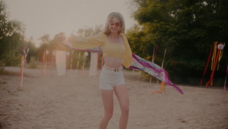 una mujer rubia alegre balanceando un sarong en la playa.