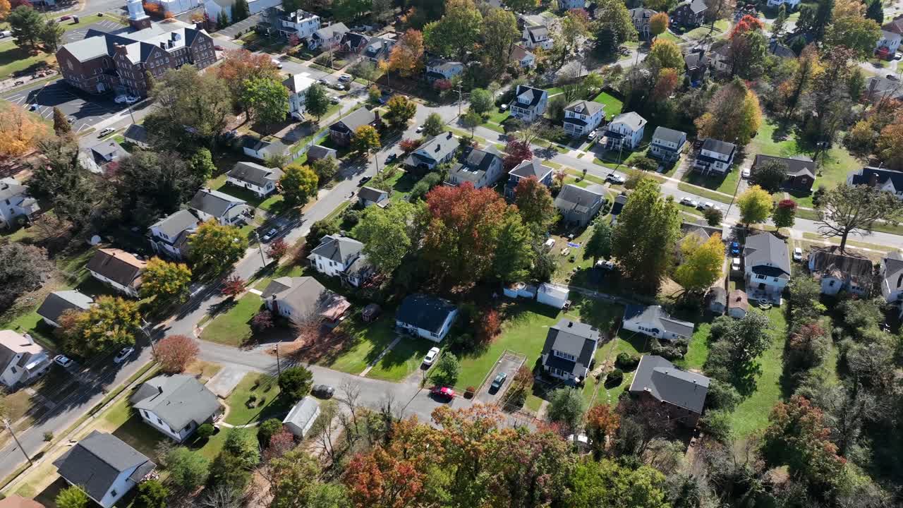 Aerial top down shot of american neighborhood with villas during sunny day. Idyllic day in fall season with colored trees. Virginia, USA. Driving cars in main street of Suburbia.