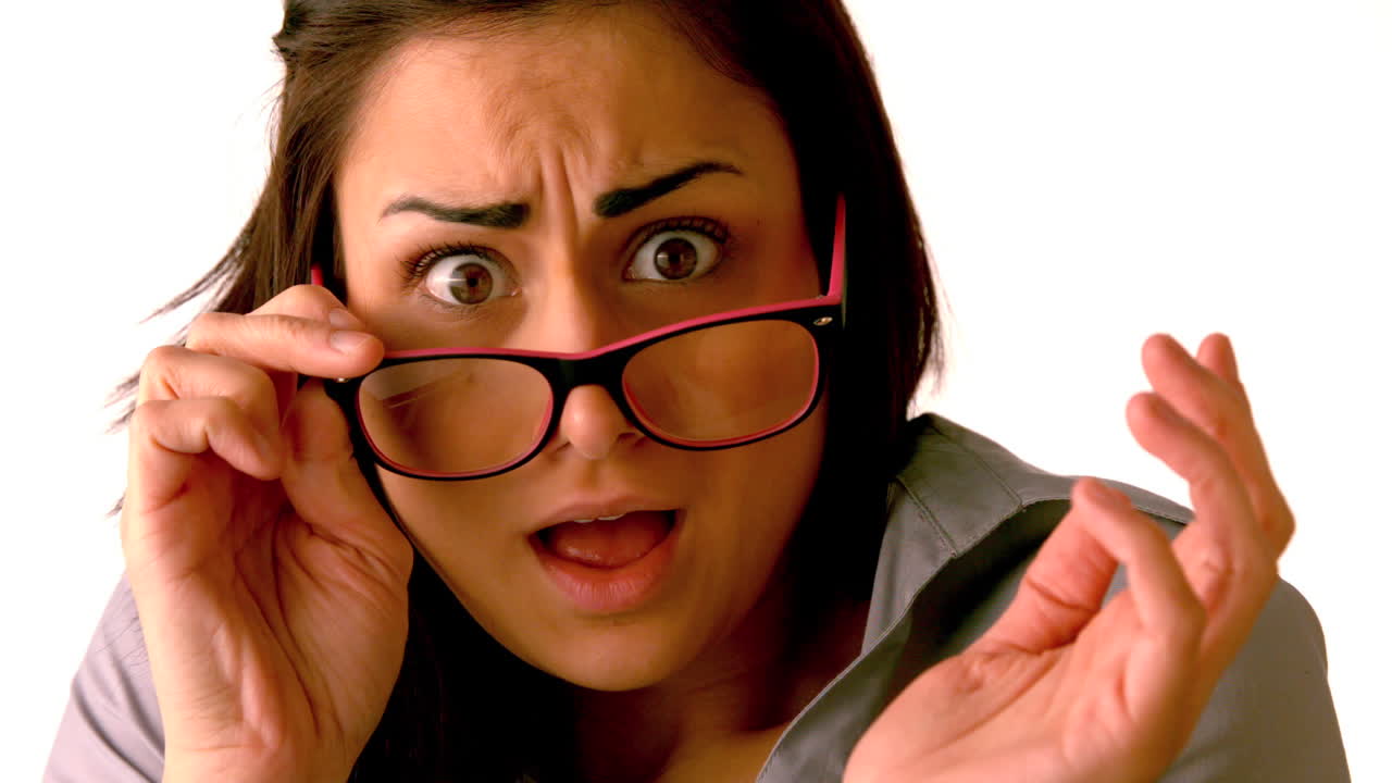 una morena conmocionada inclinando sus gafas