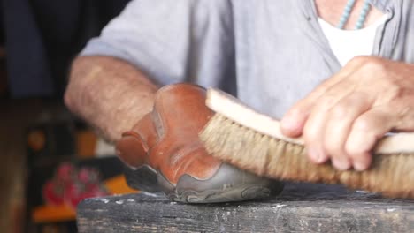 a man cleaning a brown leather shoe with a brush