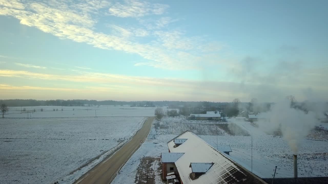 Drone view flying over snowy rooftops of a winter rural farmland