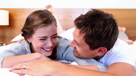 Happy-couple-lying-on-bed-and-laughing