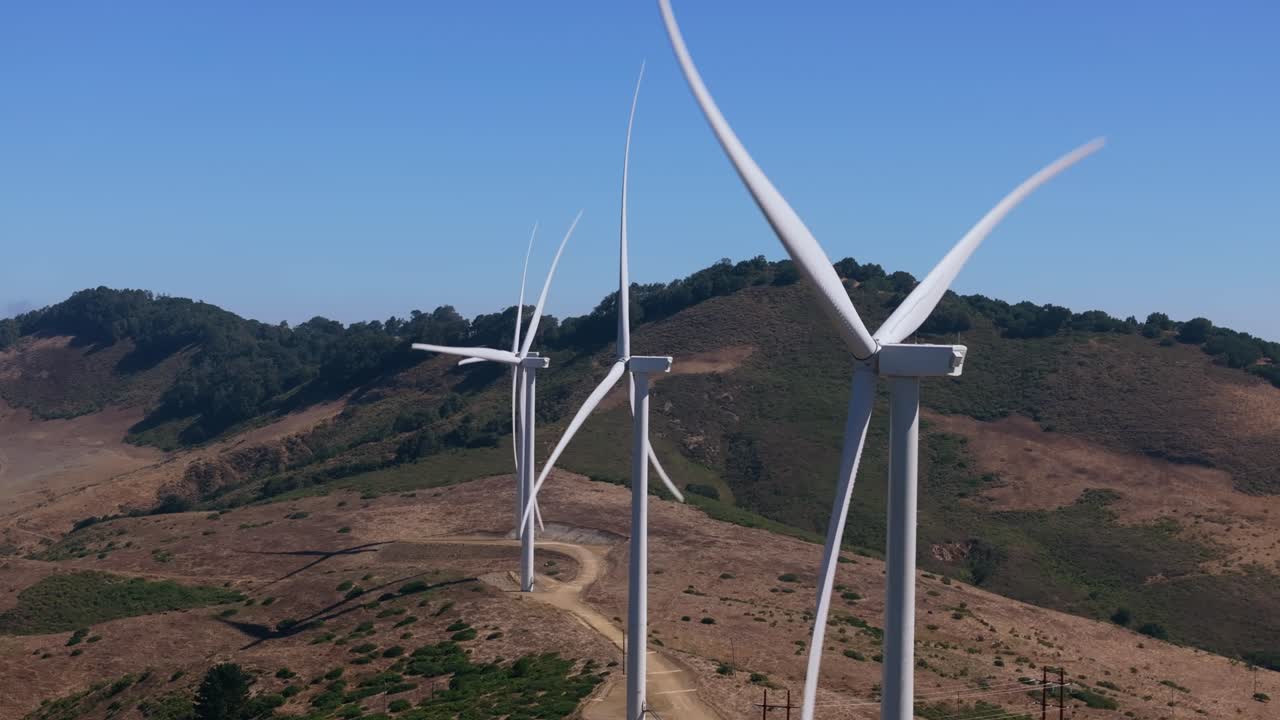 Wind turbines spinning in California hills on a sunny day