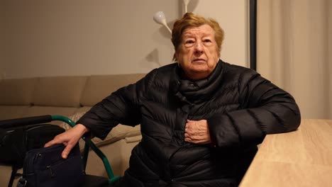elderly woman preparing to go outside wearing jacket and picking up bag indoors