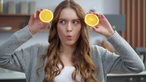 emotional girl making faces with oranges at kitchen. woman changing emotions