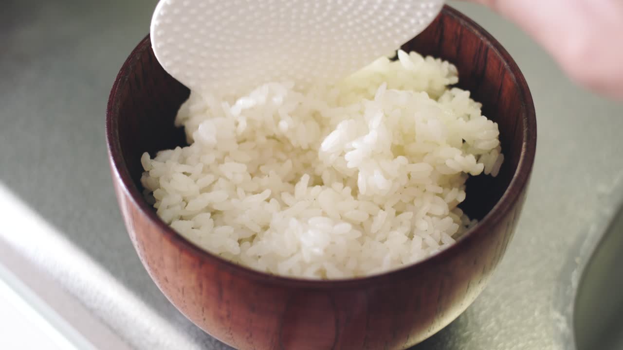 Putting White Rice Into A Wooden Bowl.  - close up shot