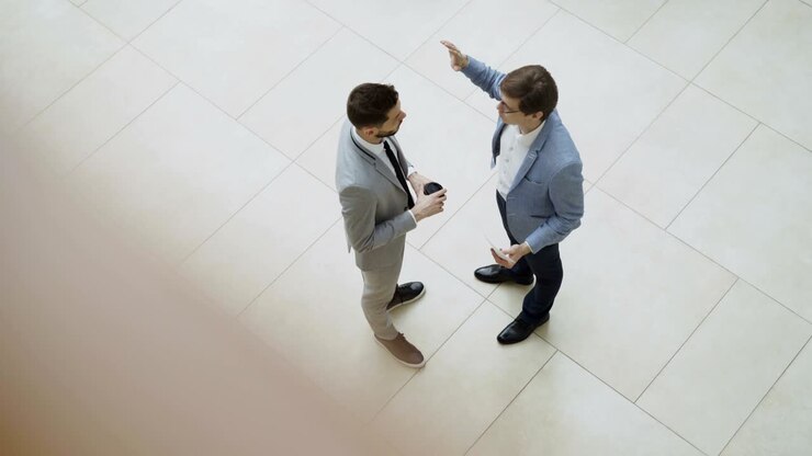 Vista dall'alto di due uomini d'affari che chiacchierano e discutono un rapporto finanziario nella hall di un centro direzionale.