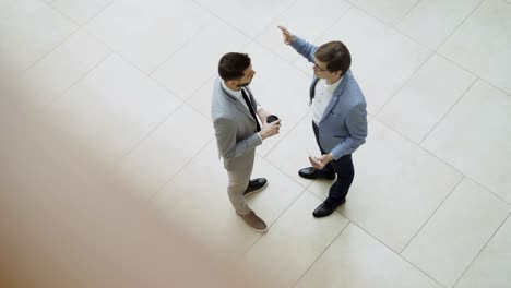 vista superior de dos hombres de negocios hablando y discutiendo el informe financiero de pie en el vestíbulo del centro de negocios