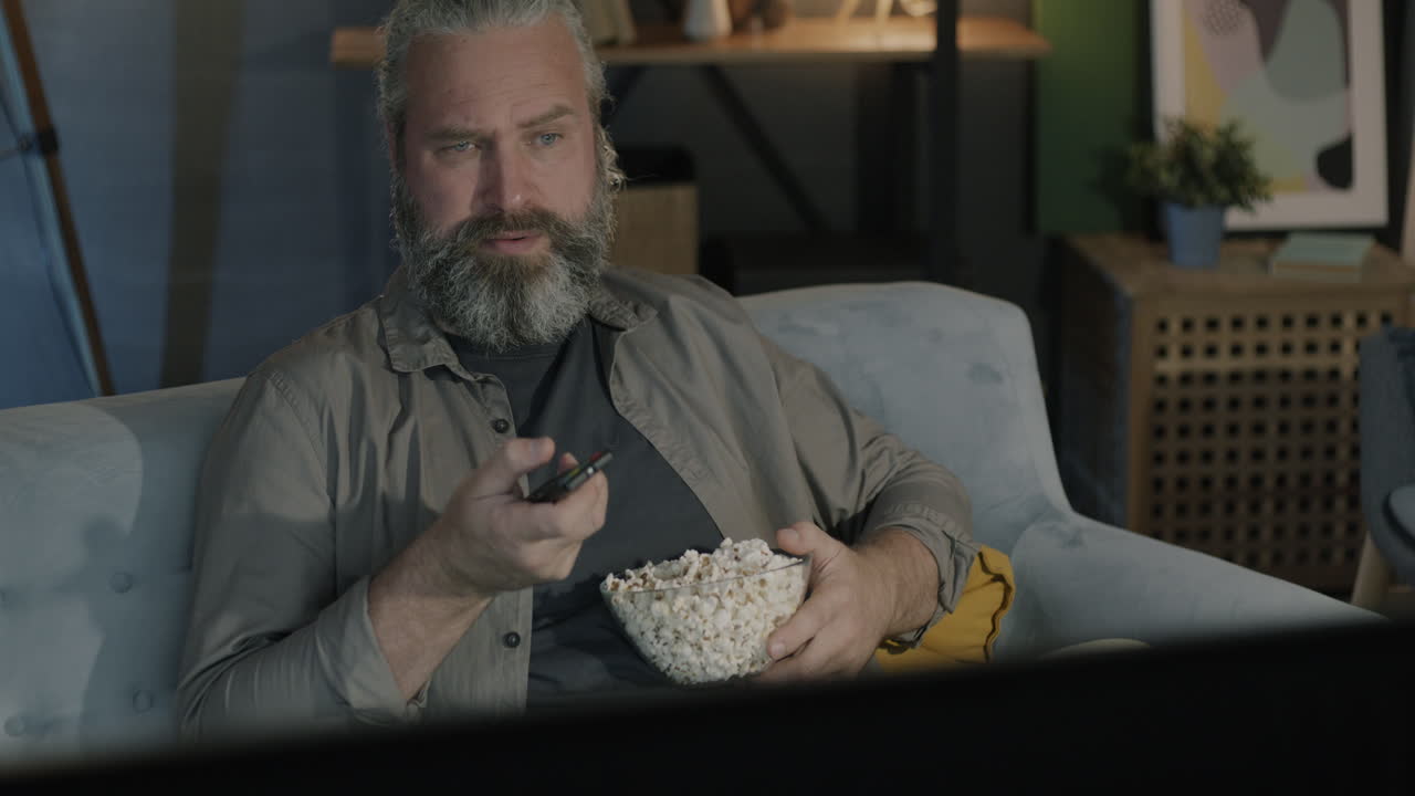 Mand ser tv med popcorn