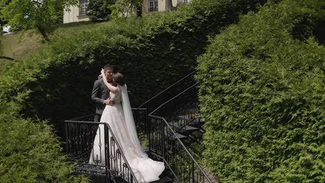 Newlyweds,-caucasian-groom-with-bride-stay-on-stairs-in-park,-wedding-couple,-man-and-woman-in-love