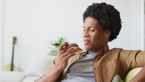 Glücklicher-Afroamerikanischer-Mann,-Der-Zu-Hause-Sein-Smartphone-Nutzt