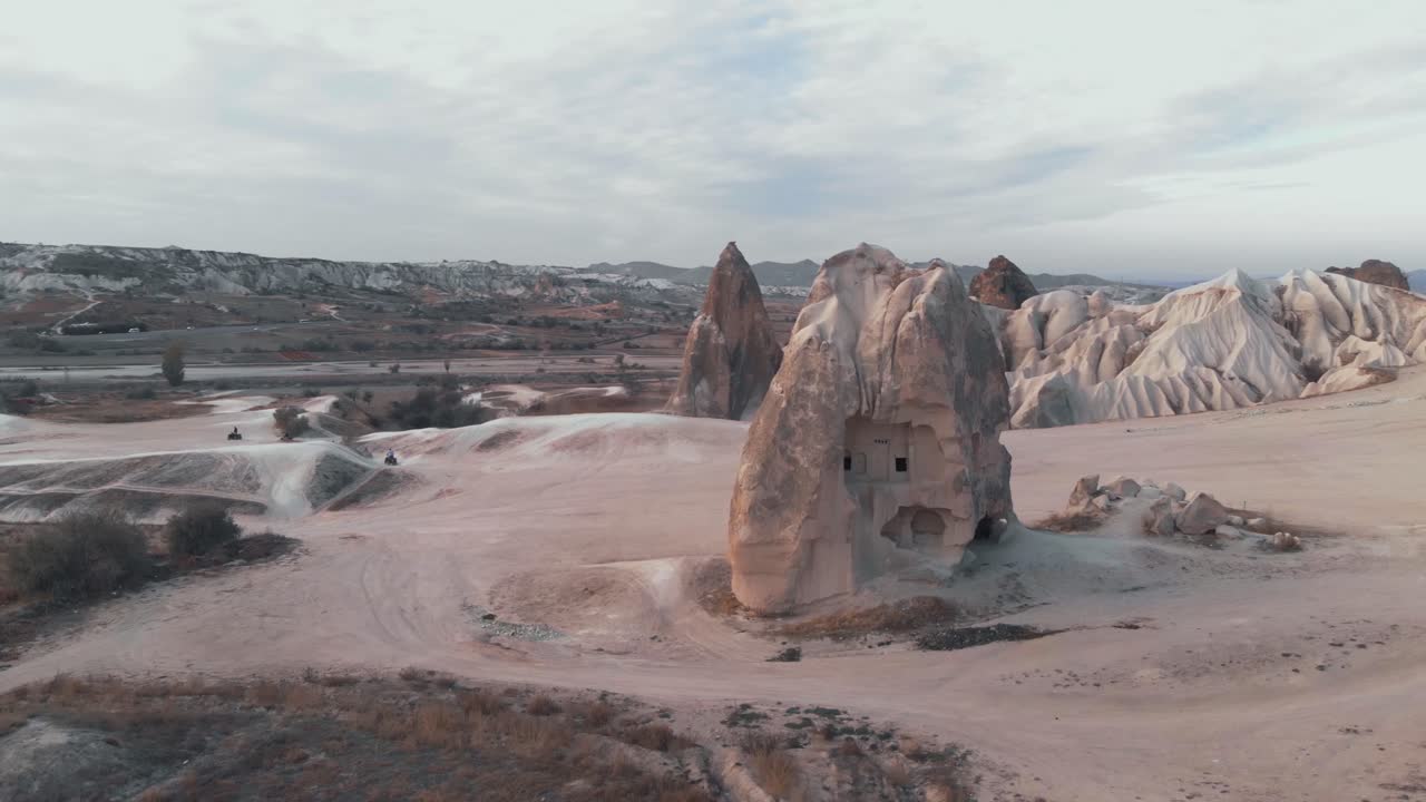 터키 카파도키아(cappadocia)의 전통 가옥이 있는 치솟는 암석이 있는 황량한 풍경 - 낮은 각도 궤도 공중