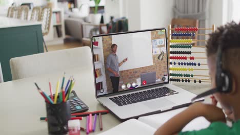 Diverse-schoolboy-having-laptop-video-call-with-male-teacher-in-slow-motion