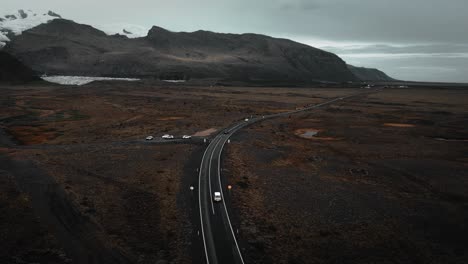 aerial tracking jeep driving on road, rocky volcanic mountain nature, epic moody dark landscape scenery iceland