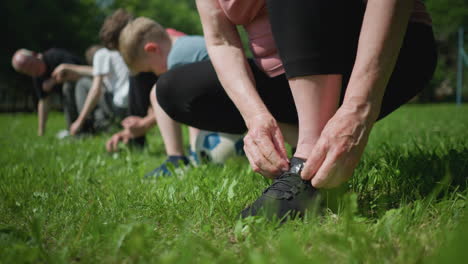 close-up of someone tying shoelace gets up with a blur view of other people kneeling down as some are tying their shoelace and others are not