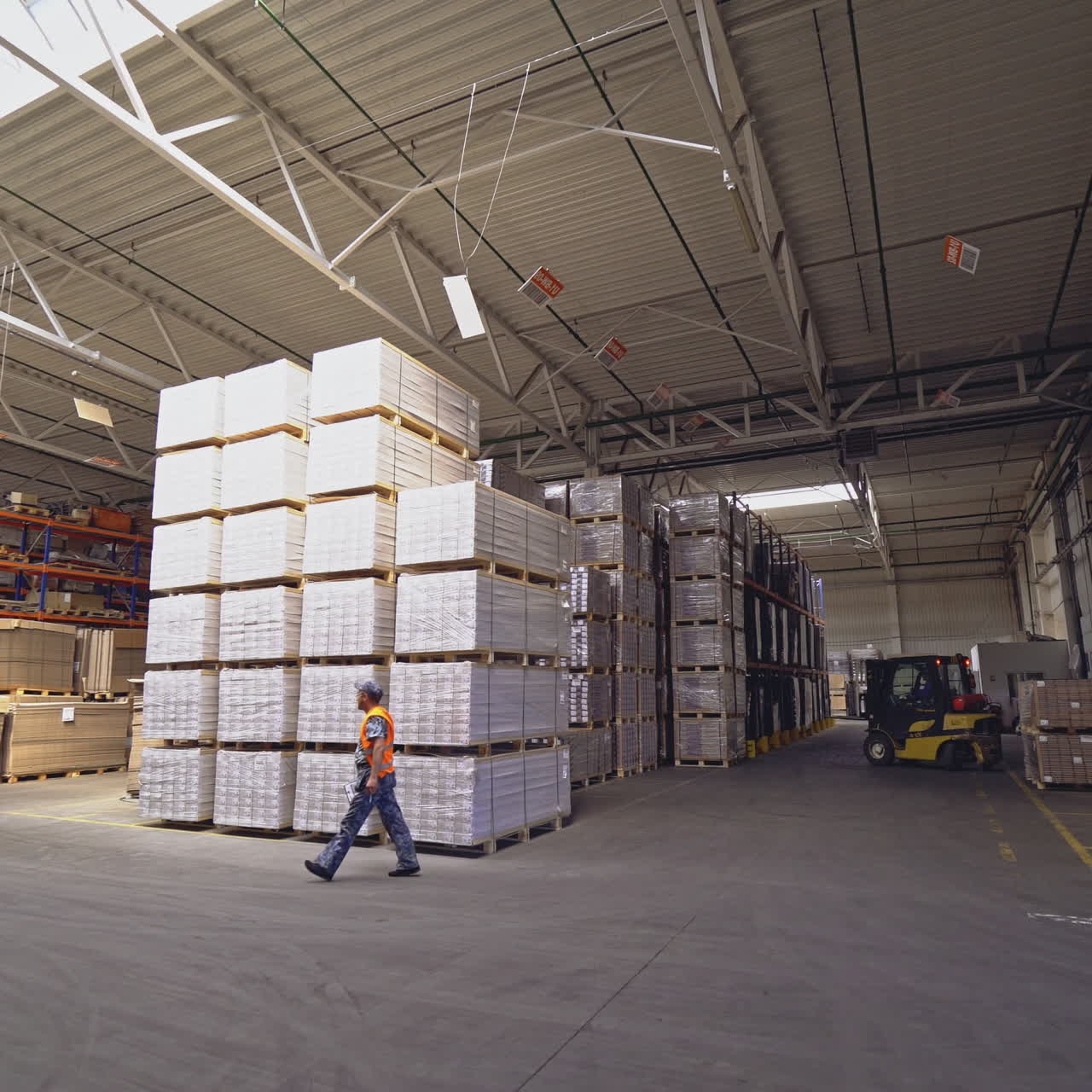 Storekeeper deploys the loader and lifts the hydraulic forks to picks up the cargo on the shelf in the storage.