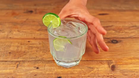 Detailed-shot-of-a-perfectly-crafted-gin-and-tonic-cocktail,-elegantly-placed-on-a-wooden-table-in-a-restaurant