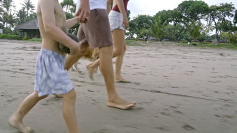 family walking on bali beach and playing with dog