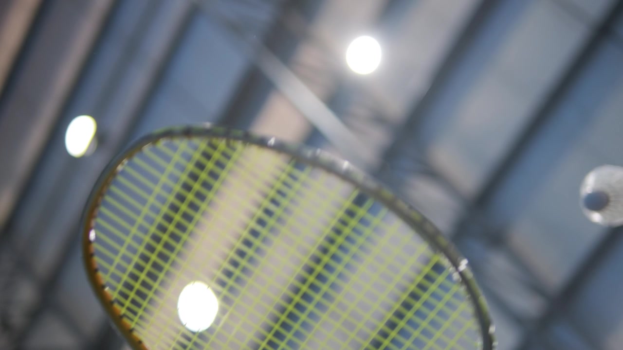 Playing badminton, close-up close motion view of racket and birdie.