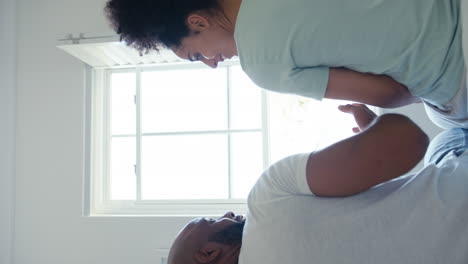 vertical video of loving couple wearing pyjamas sitting on bed and looking out of window