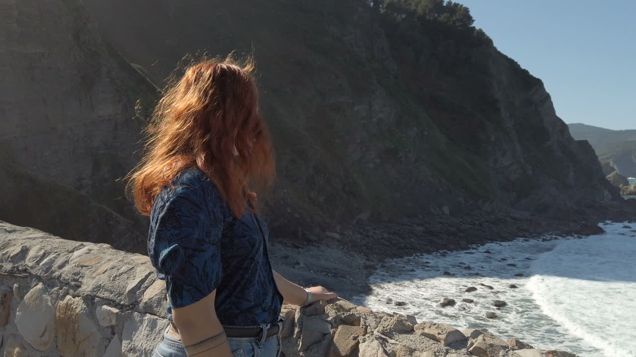 Woman overlooking the sea from a rocky coast