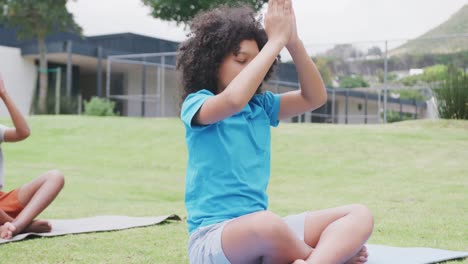 video of diverse schoolgirl and schoolboy practicing yoga meditation in outdoor class, copy space