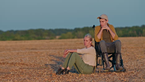 couple in wheelchairs in a field at sunset