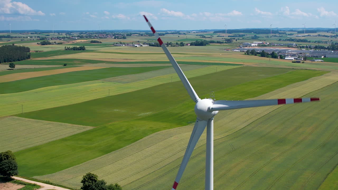 녹색 농장 토지로 둘러싸인 회전하는 풍력 터빈의 정적 항공 사진