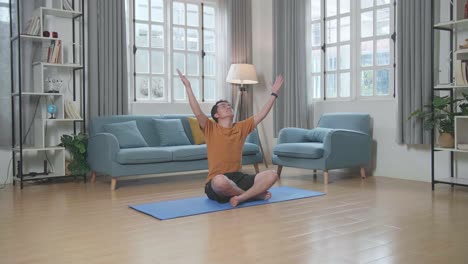 아시아인 남자가 집에서 마트 위에서 수카사나 요가 포즈를 취하고 있습니다.