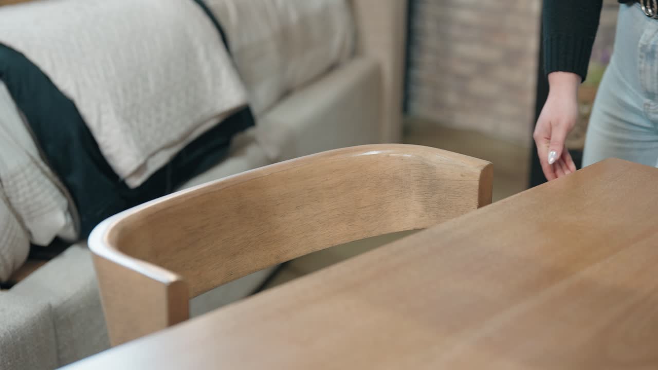 Static store shot shows shopper sliding stylish chair out, checking seat finish