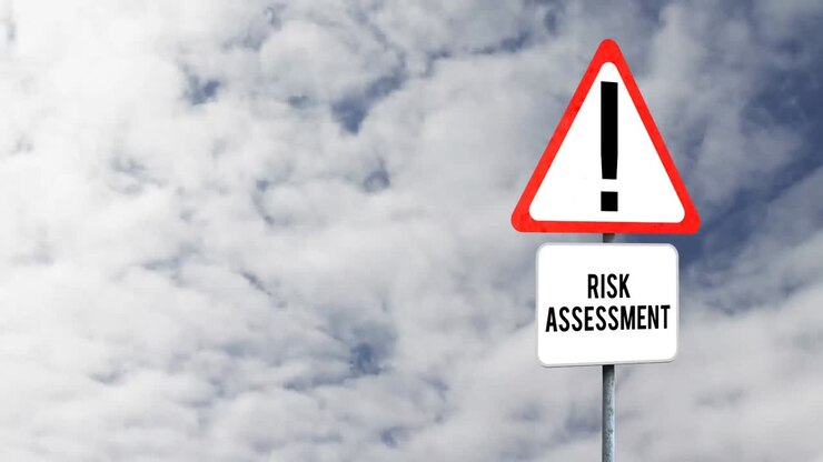 Attention signboard post with risk assessment text against clouds in the blue sky
