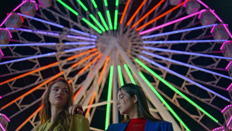 closeup beautiful girls posing at colorful ferris wheel. fashion models at night