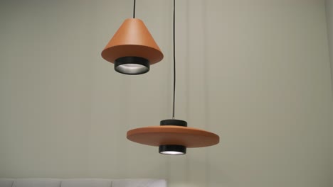 two hanging pendant lights with a modern design, featuring terracotta shades and black accents, cast a warm glow against a neutral backdrop, enhancing the contemporary feel of the space