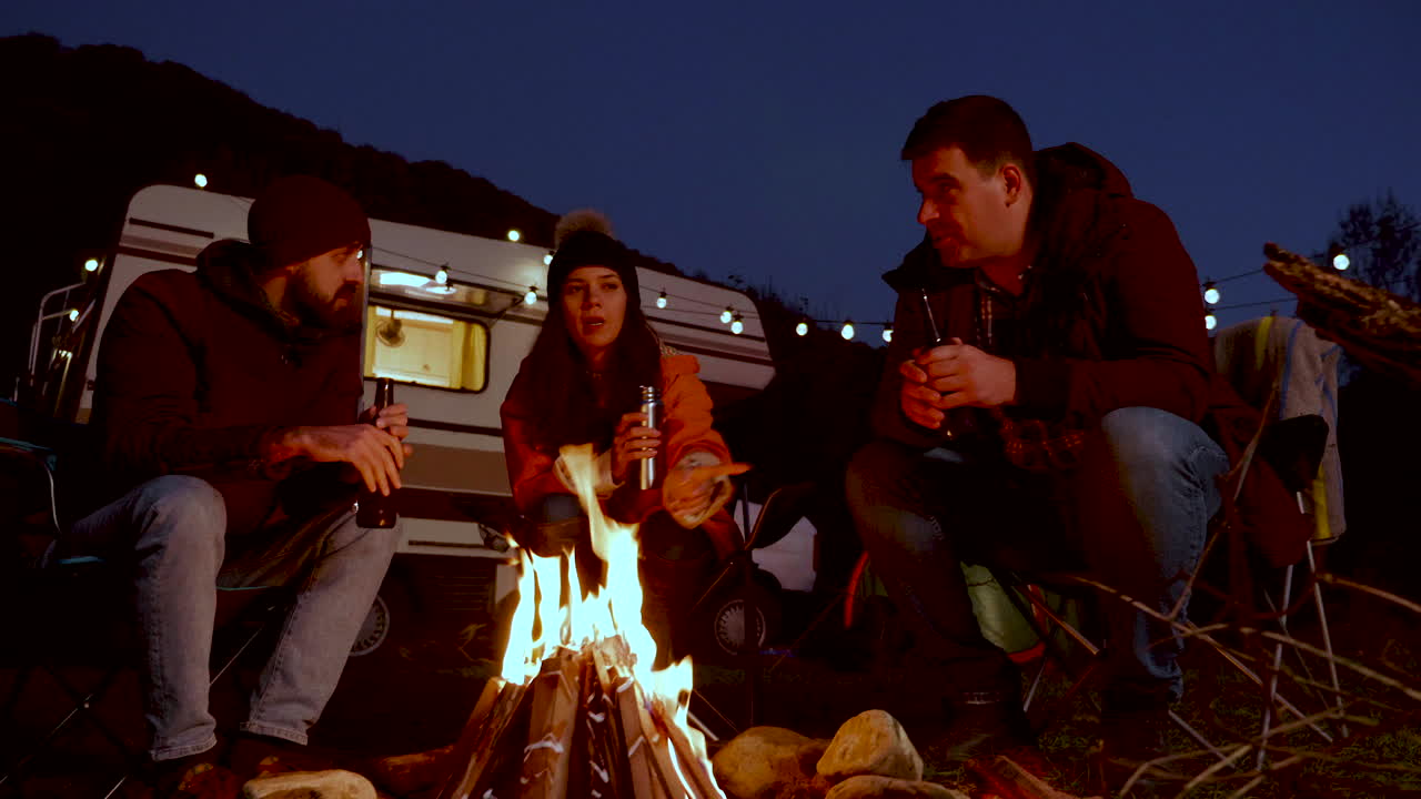 백인 친구 가 레트로 캠퍼 앞 에서 함께 맥주 를 마시고 있다
