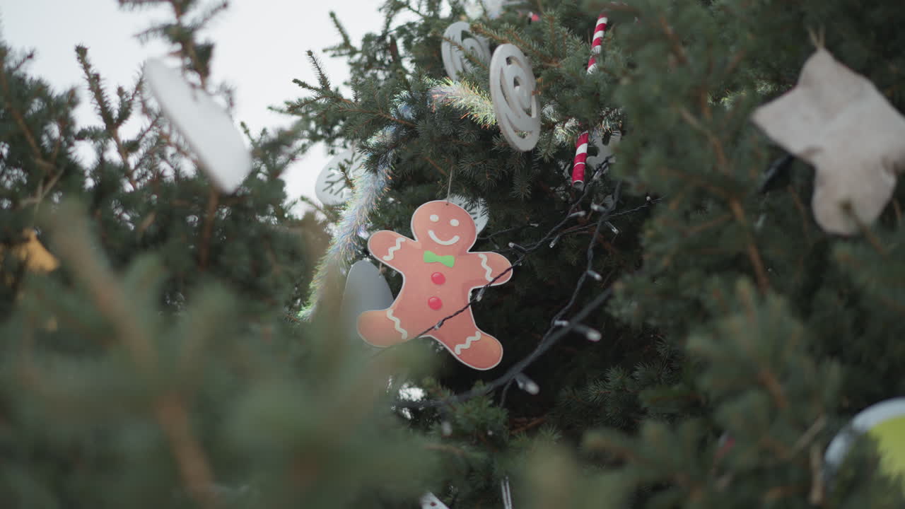 Upward view of beautifully decorated christmas tree featuring ornaments, festive lights, and tinsel, sunlight illuminates green pine branches, with a blurred foreground