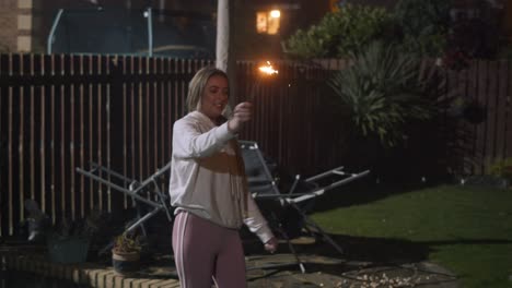 blonde girl having fun with sparkler in hand. handheld