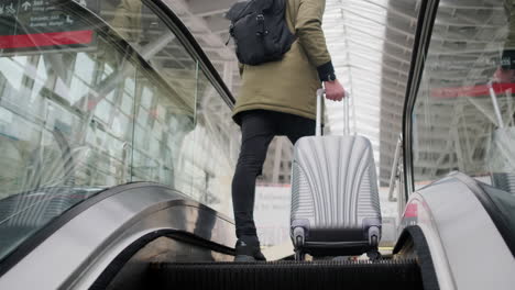 person with luggage on an escalator in an airport