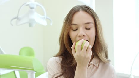 Mujer-Feliz-Comiendo-Manzana-En-La-Clínica-Dental.-Paciente-Sonriente-En-El-Consultorio-Del-Dentista.
