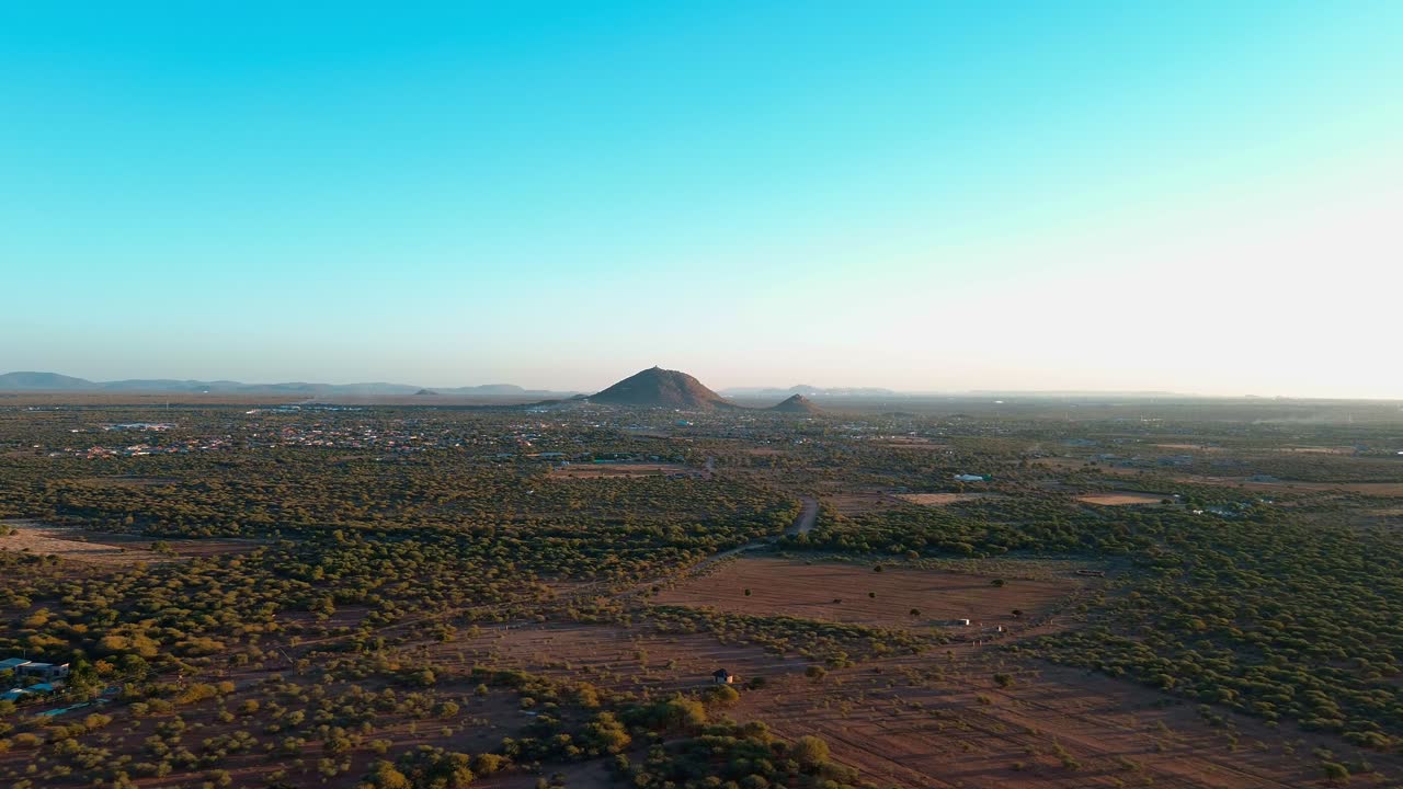 풍부한 파란 하늘, 초록색 식물과 갈색 - 오렌지색 토양으로 둘러싸인 산꼭대기를 향해 나아가는 드론 촬영