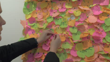 woman pinning a piece of paper with heart onto the wish board