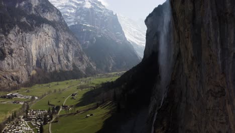 Aerial-flying-sidewards-showing-Lauterbrunnen-and-the-waterfall-on-a-sunny-day,-Switzerland