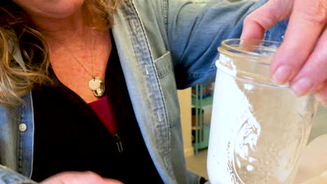 woman recycling glasses and mason jars by painting them and using them as decoration and vases