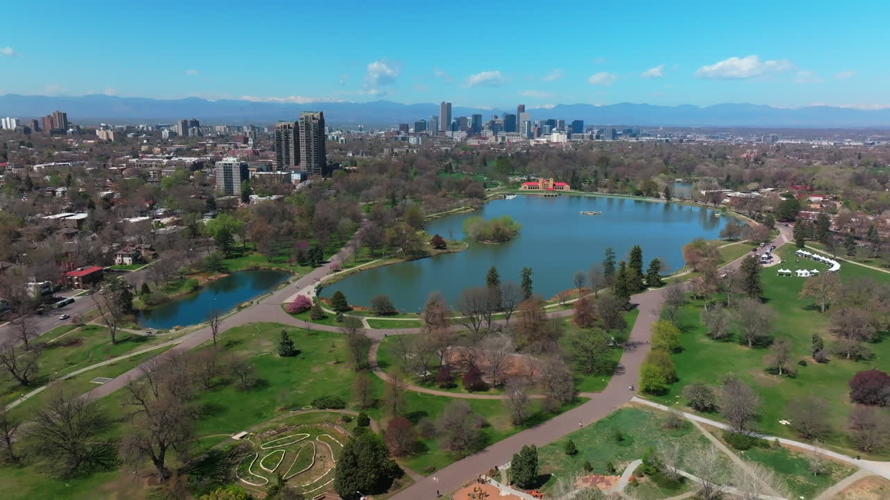 Denver City Park early spring snowcapped Rocky Mountains downtown cityscape aerial drone Colorado green lush grass Ferril Duck Lake sunny blue skies morning skyscrapers neighborhood up circle left