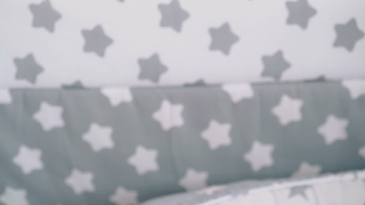 mother rocks newborn baby in crib with sleeping cocoon