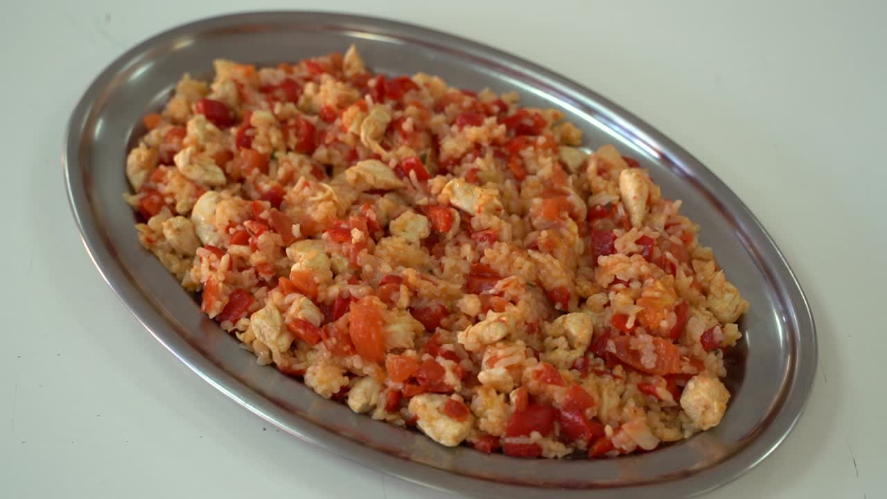 Djuvec composto da pollo, pomodori e riso in un grande piatto ovale - Statico, Primo piano