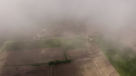 aerial drone moves through clouds above grassland and farmland in midwest of united states