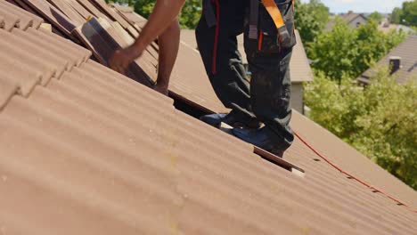 roof worker preparing rooftop tiles to install solar panels, side view