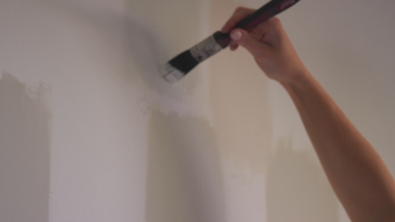 primer plano de una mujer decorando una habitación en la casa probador de pintura tiras de color de pintura en la pared