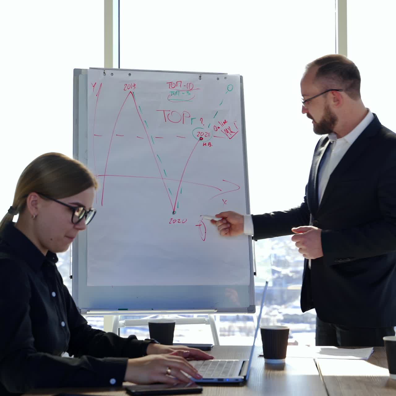 Businessman speaking to a partners. Entrepreneur in suit showing on a written board while talking about the new strategy in office centre in the city